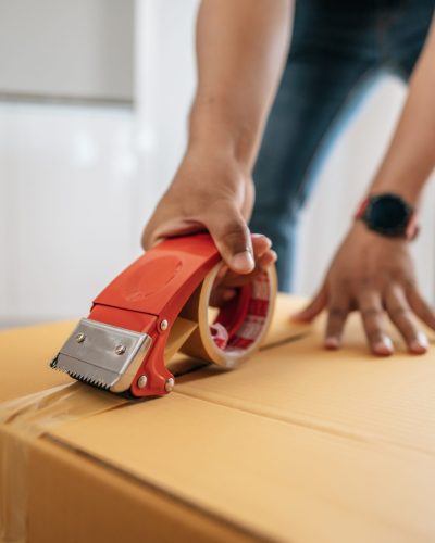 Close up hand of man use glue tape to close cardboard box, sealing big box for packing moving, new house concept, Selective focus	cardboard box,